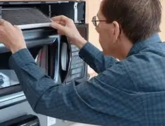Appliance repair technician replacing a microwave vent filter in Austin, TX